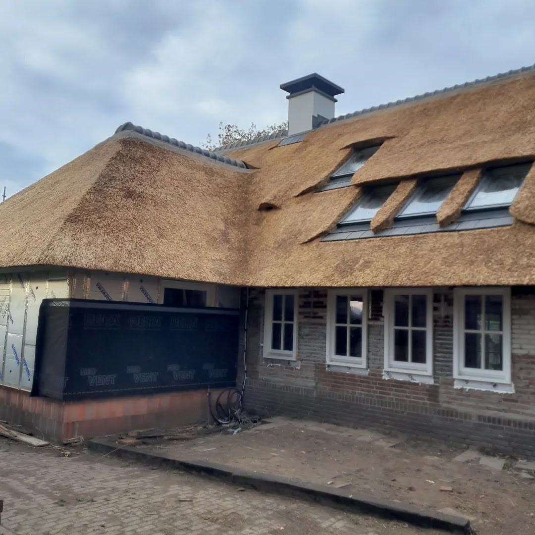 Vers gedekt lang rieten dak met drie dakkapellen boven een bakstenen gevel